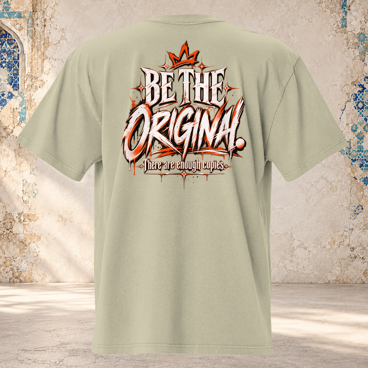 Back mockup of a faded eucalyptus oversized tee with a crown and cream and orange "BE THE ORIGINAL." lettering