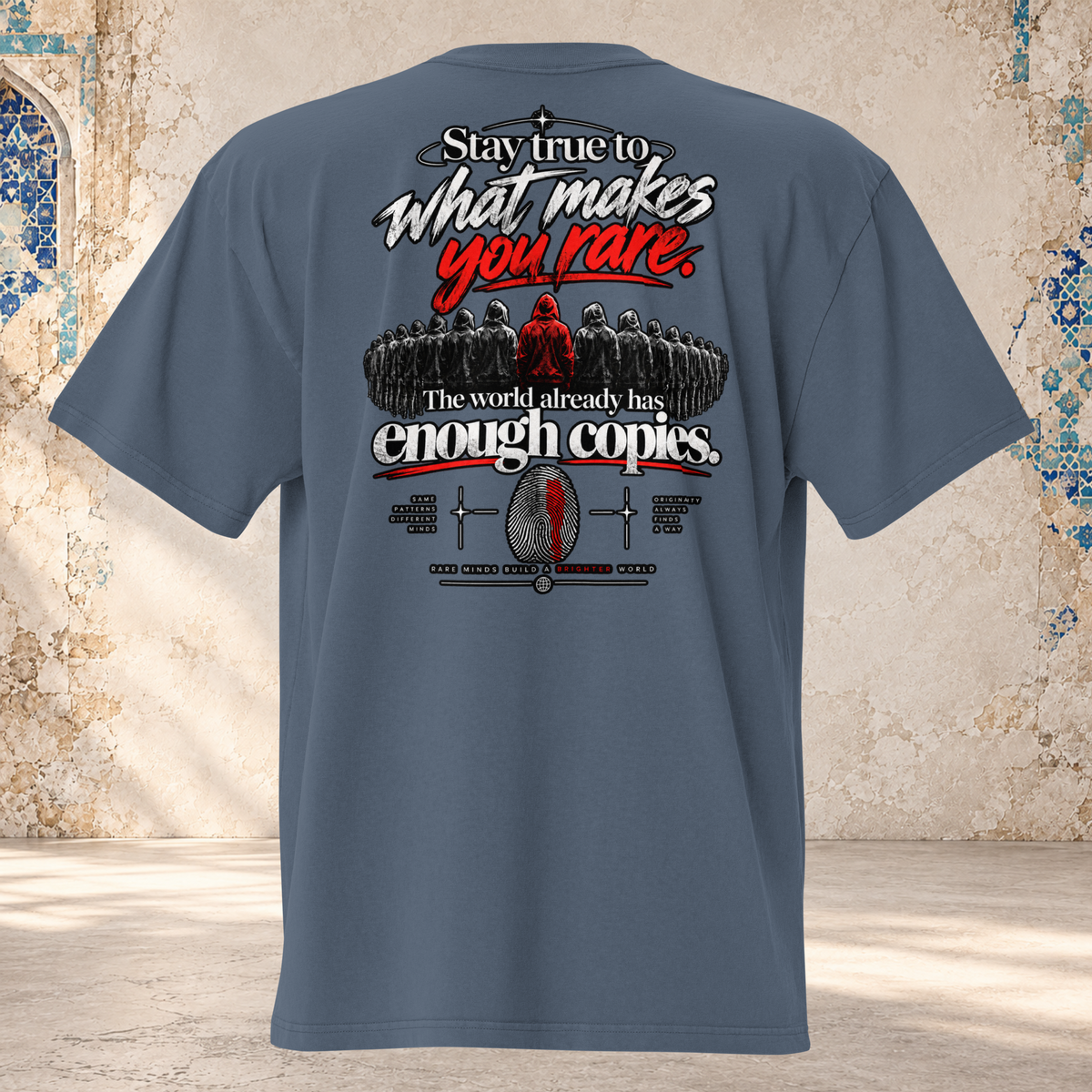 Back mockup of a faded indigo oversized tee with a dark crowd, one red figure and "Stay true to what makes you rare." lettering