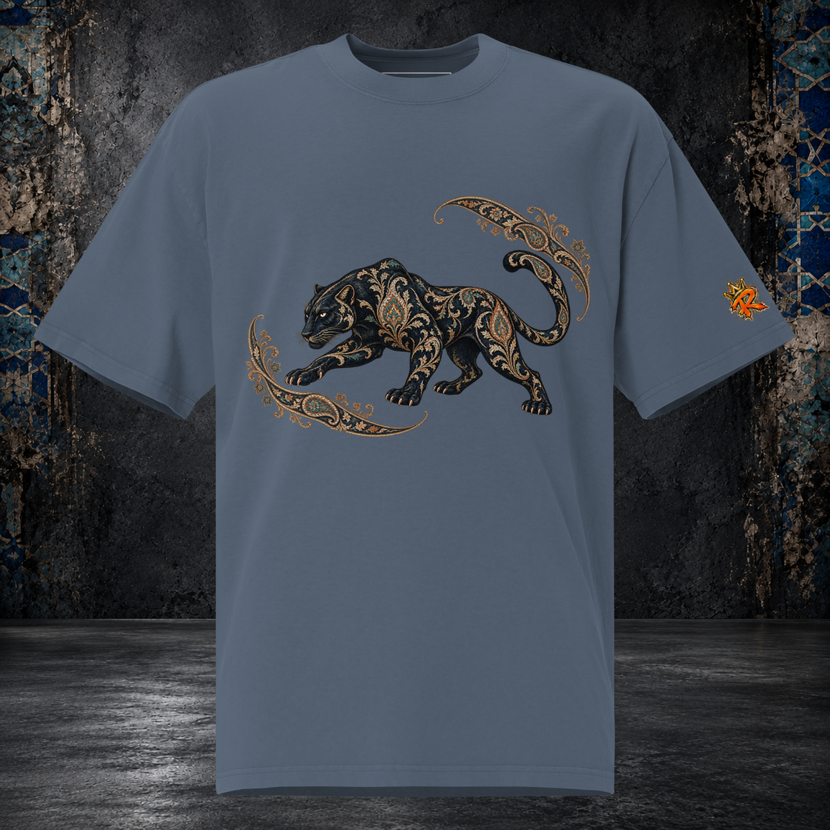Front mockup of a faded indigo oversized tee with a black panther, gold-toned ornament and curling paisley flourishes