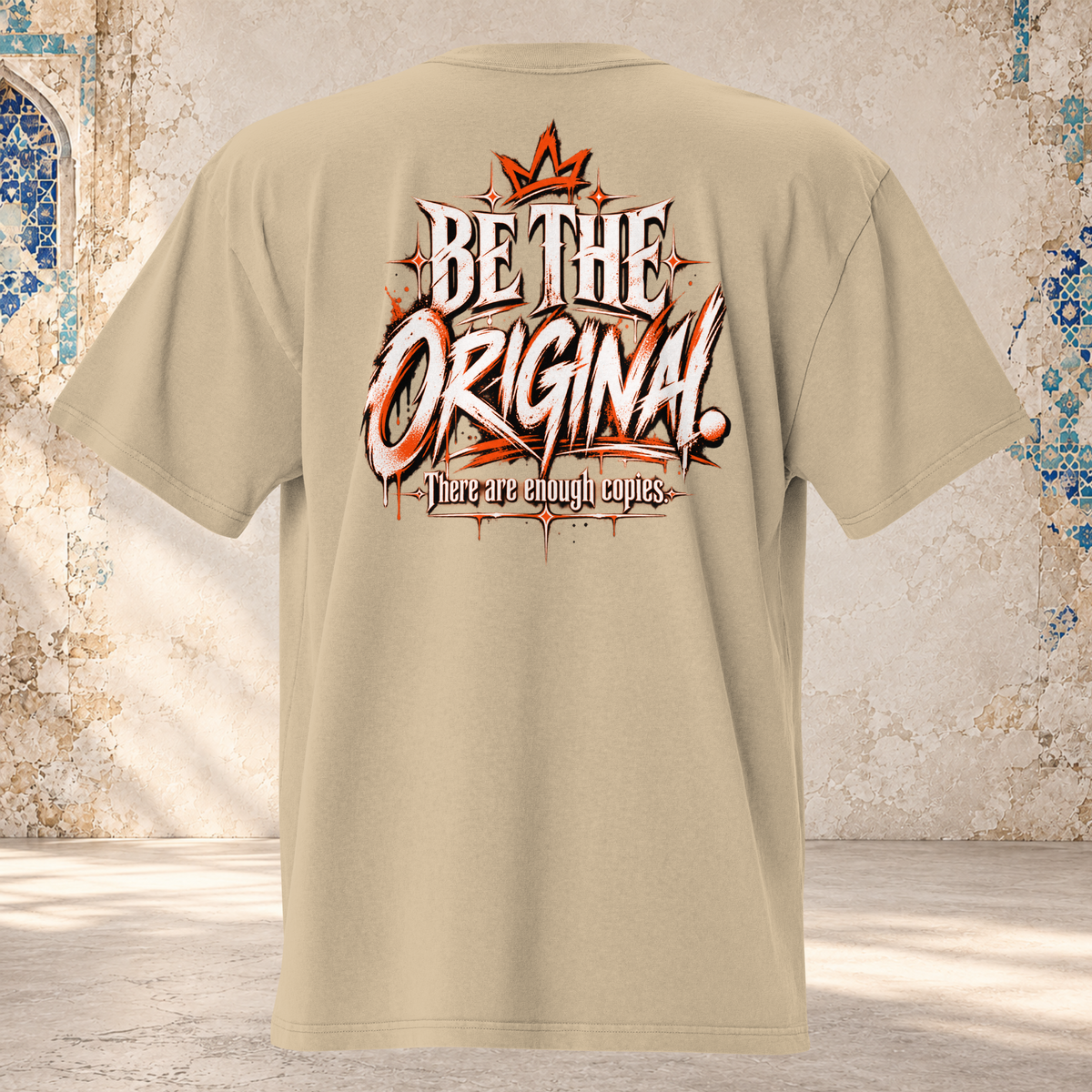 Back mockup of a faded khaki oversized tee with a crown and cream and orange "BE THE ORIGINAL." lettering
