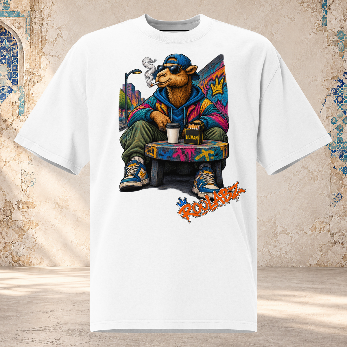 Front mockup of a faded white oversized tee with a camel in sunglasses and a blue cap seated on a graffiti-covered chair