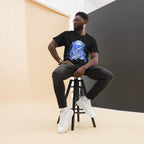 Model seated on a stool wearing a black Blue Astronaut graphic tee, dark trousers and white high-top shoes