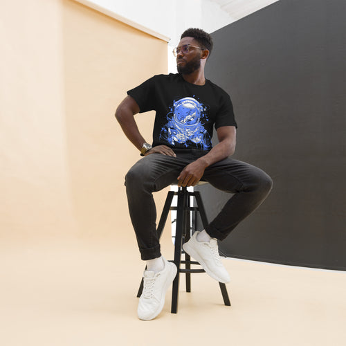 Model seated on a stool wearing a black Blue Astronaut graphic tee, dark trousers and white high-top shoes