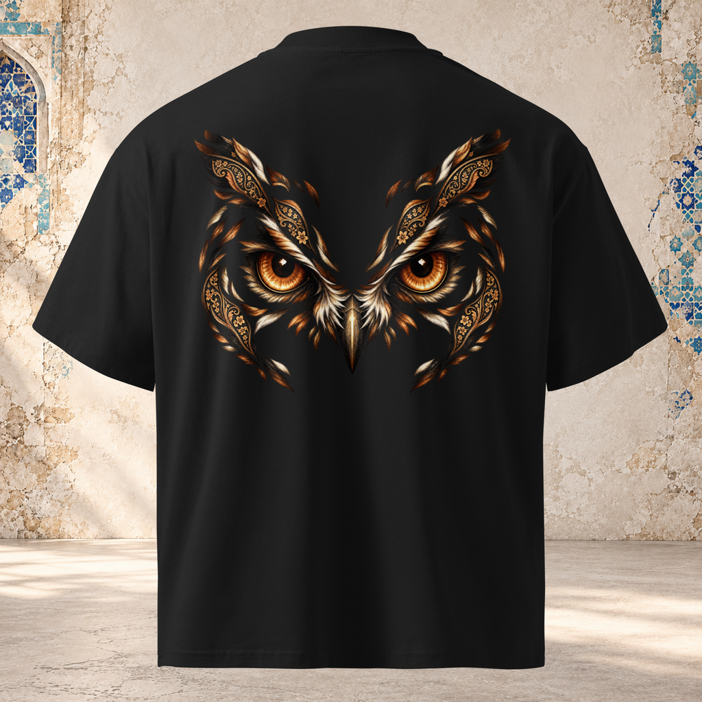 Back view of a black oversized tee with an owl's amber eyes framed by copper feathers and paisley shapes