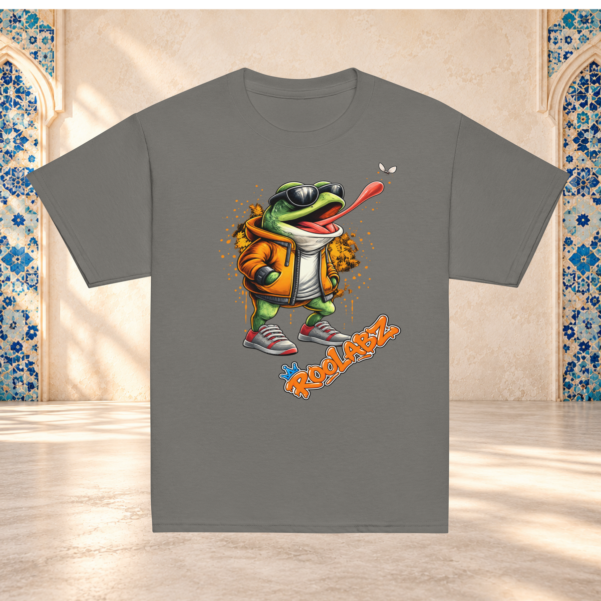 Charcoal youth tee mockup with a frog in sunglasses chasing a fly, displayed against a tiled archway