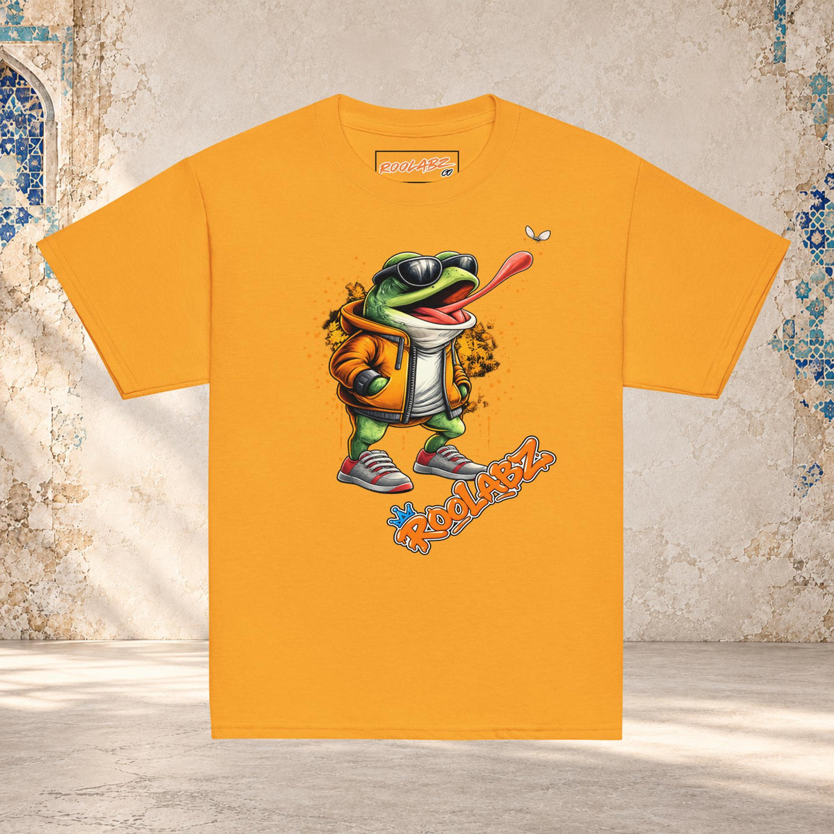 Front mockup of a gold youth tee with a frog in sunglasses reaching its tongue toward a fly