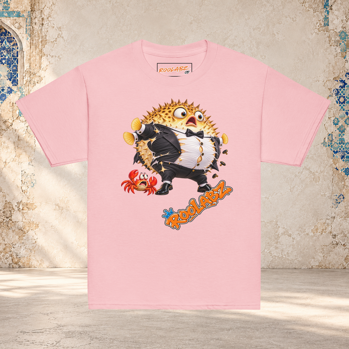 Front mockup of a light pink youth tee with a puffed-up pufferfish bursting out of a black and white tuxedo